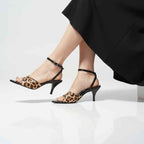 high heeled shoes Leopard print  worn with a black skirt on a white background
